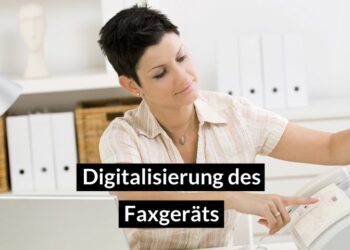 Eine Frau sitzt am Schreibtisch und führt ein Blatt Papier ins Faxgerät ein