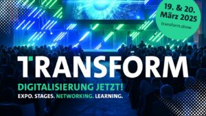 Schriftzug "Transform" vor einer grün-blau beleuchteten Bühne mit Publikum