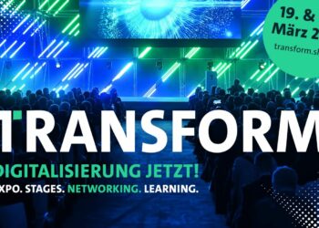 Schriftzug "Transform" vor einer grün-blau beleuchteten Bühne mit Publikum